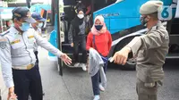 Petugas mengarahkan penumpang yang turun dari bus Antar Kota Antar Provinsi (AKAP) di Terminal bus Kalideres, Jakarta Barat, Senin (17/5/2021). Arus balik pemudik mulai terlihat di sejumlah terminal di Jakarta, salah satunya di Terminal Kalideres. (Liputan6.com/Angga Yuniar)