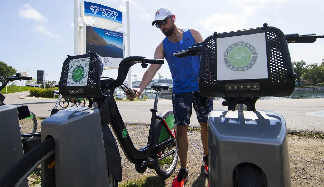 Seorang pria memindai kode untuk mengambil sepeda sewaan di sebuah pos parkir sepeda, Toronto, Kanada, Rabu (2/9/2020). Mulai 2 September, pelanggan layanan penyewaan sepeda Bike Share Toronto dapat menikmati perjalanan gratis di kota tersebut setiap Rabu selama September. (Xinhua/Zou Zheng)
