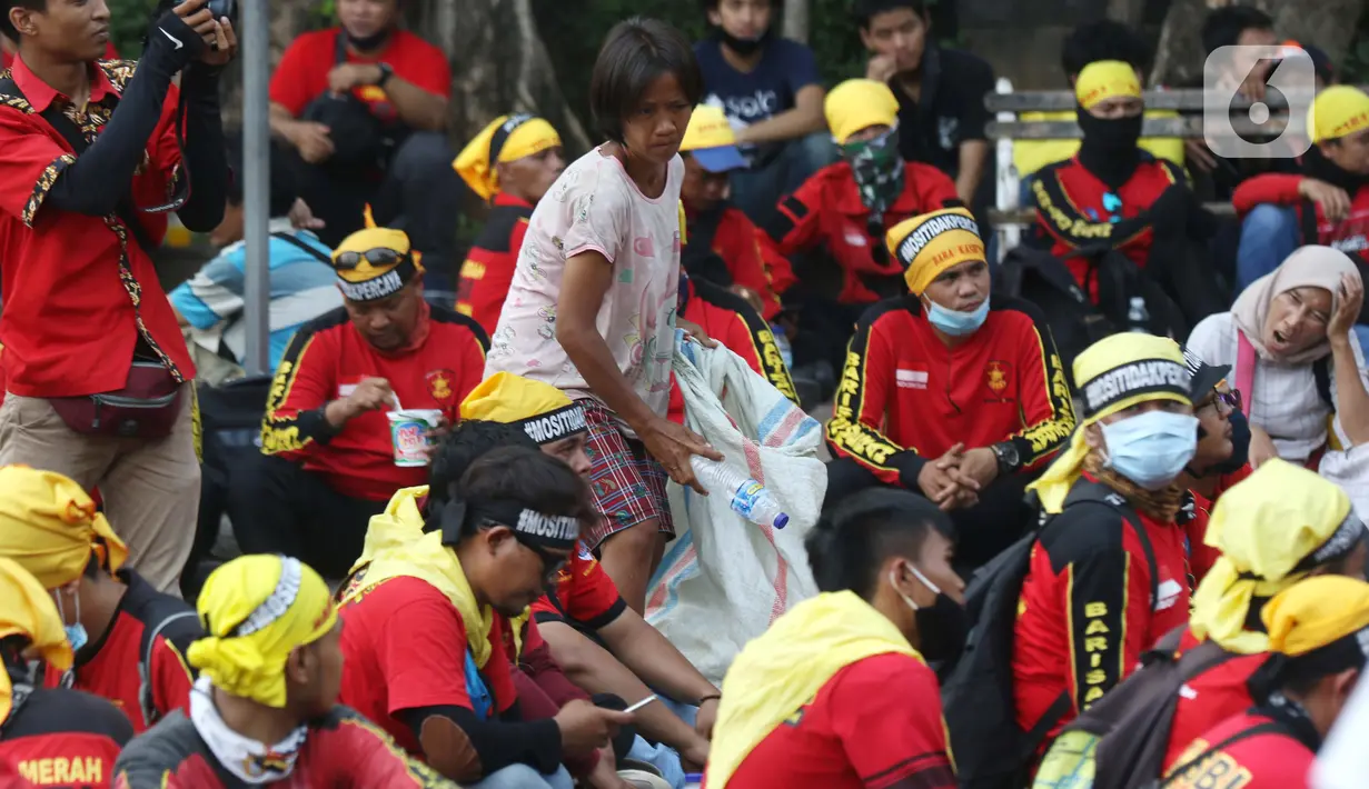Pemulung berada di tengah-tengah aksi unjuk rasa di kawasan Patung Kuda, Jakarta, Selasa (10/11/2020). Beberapa pemulung mencoba peruntungan saat massa gabungan dari berbagai organisasi buruh dan mahasiswa berunjuk rasa menolak Omnibus Law UU Cipta Kerja. (Liputan6.com/Helmi Fithriansyah)