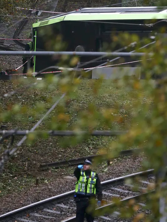 Seorang petugas layanan darurat masih berada di lokasi terbaliknya sebuah trem di Croydon, London Selatan, Inggris, Rabu (9/11). Sebanyak tujuh orang tewas dan lebih dari 50 orang mengalami luka-luka akibat trem yang keluar jalur. (REUTERS/Neil Hall)
