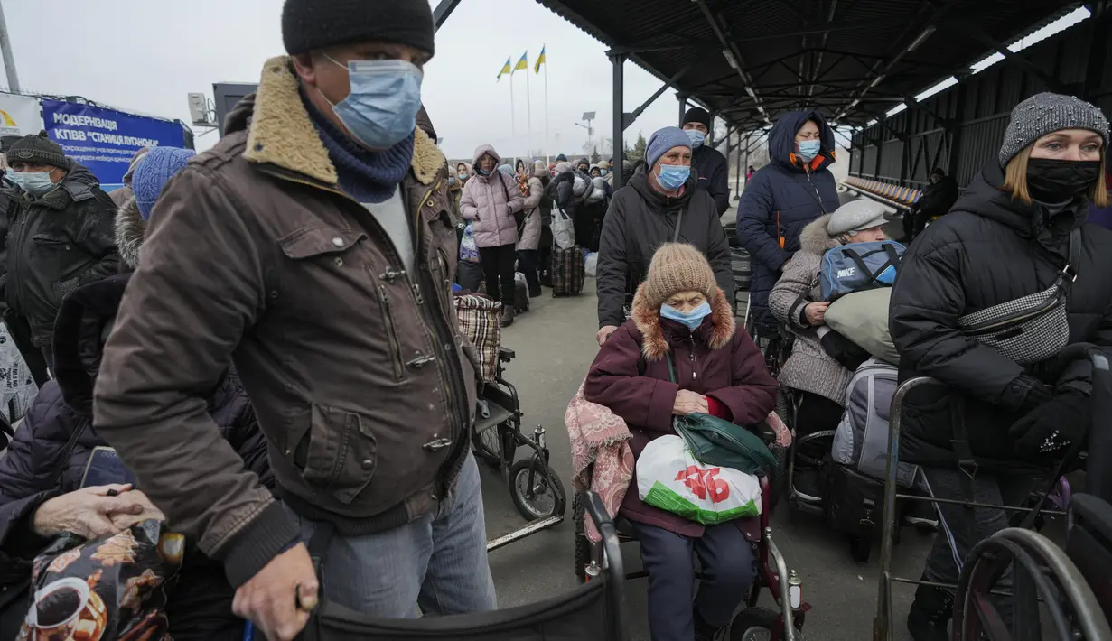 Orang-orang menunggu untuk menyeberang dari wilayah yang dikuasai pemerintah Ukraina ke wilayah yang dikuasai separatis pro-Rusia di Stanytsia Luhanska, satu-satunya titik penyeberangan yang buka setiap hari, di wilayah Luhansk, Ukraina timur, pada 22 Februari 2022. (AP Photo/Vadim Ghirda )