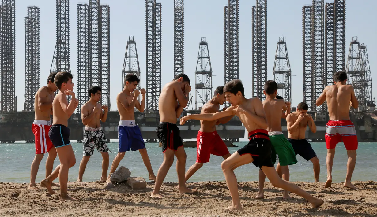 Anak-anak yang tergabung dalam sekolah kickboxing sedang berlatih di tepi Laut Kaspia dekat dengan bekas tempat pengeboran minyak era Soviet di kota Baku, Azerbaijan, Sabtu (27/6). (AP Photo/Dmitry Lovetsky)