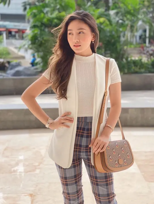 Sebagai outfit kasual, Natasha Wilona memadukan knit shirt denga pleated pants dan vest berwarna putih. Sebagai sentuhan akhir, Natasha mengenakan crossbody bag Gucci hasil kolaborasi dengan Disney.