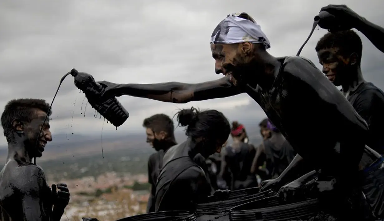 Seorang peserta menyiramkan minyak dan cat hitam ke rekannya saat Festival Cascamorras di Baza, Spanyol, 6 September 2015. Festival ini diadakan setiap 6 September tiap tahunnya dan telah dilakukan selama 500 tahun terakhir. (AFP PHOTO/JORGE GUERRERO)