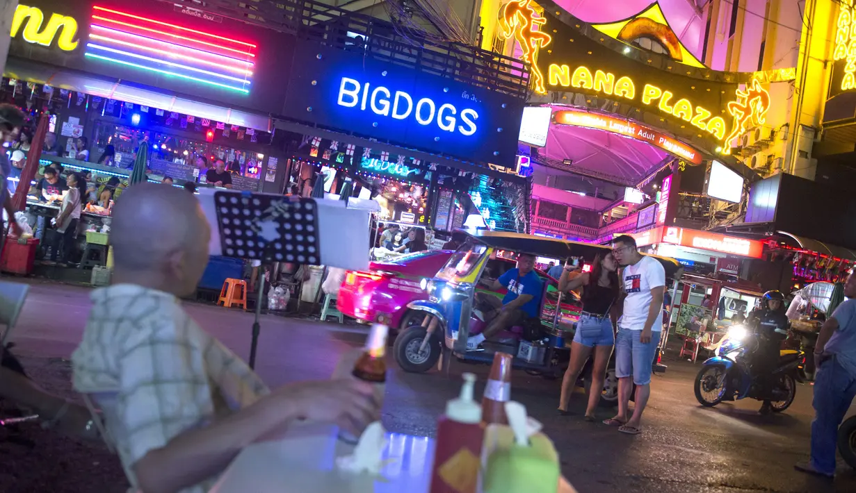 Foto pada 11 Oktober 2018 memperlihatkan seorang pria minum bir di luar bar di Nana Red Light Distrik, Bangkok, Thailand. Kawasan tersebut merupakan tempat lokalisasi hiburan malam paling tersohor di Bangkok. (Romeo GACAD / AFP)