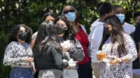 Orang-orang mengenakan masker saat menunggu di halte bus di sepanjang Hill Street, Los Angeles pada Rabu (13/7/2022). Los Angeles County mungkin memberlakukan mandat masker pada 29 Juli 2022 jika jumlah COVID-19 terus meningkat. (AP Photo/Marcio Jose Sanchez)