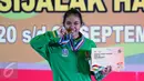 Lifter Jatim, Acchedya Jagaddhita menggigit medali emas usai berlomba di kelas 58kg PON XIX Jabar di Gymnasium Si Jalak Harupat, Kab Bandung, Rabu (21/9). Acchedya meraih emas dengan total angkatan 201kg. (Liputan6.com/Helmi Fithriansyah)