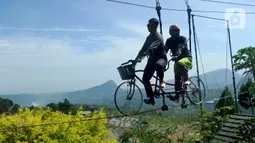 Wisatawan menjajal wahana sepeda gantung saat mengunjungi tempat wisata yang Instagrammable di kawasan Puncak Dua, Sukamakmur, Bogor, Jumat (6/1/2023). Meski kawasan Puncak Dua belum dikembangkan secara maksimal oleh Pemkab Bogor dan pemerintah pusat, warga seputar Jabodetabek dan Cianjur tetap antusias mengunjungi kawasan ini sebagai tempat wisata alternatif selain kawasan Puncak dan sekitarnya yang selalu didominasi kemacetan lalu lintas. (merdeka.com/Arie Basuki)