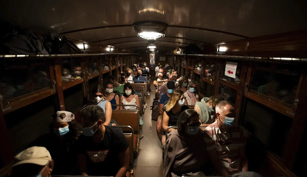 Penumpang menaiki kereta Palma-Soller di Pulau Balearic Spanyol Mallorca (14/7/2021). Kereta dan lokomotif mempertahankan desain aslinya, dengan pemeliharaan dan perbaikan dilakukan di bengkel kereta api itu sendiri, dengan menghormati model awal. (AFP/Jaime Reina)