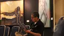 Pengunjung membaca katalog di depan lukisan pada acara pembukaan pameran 4 pelukis bersama yang bertajuk "Spirit Indonesia", di Galeri Cipta 3, TIM, Jakarta, Sabtu (7/3). Pameran tersebut berlangsung hingga 15 Maret 2015. (Liputan6.com/Helmi Afandi)
