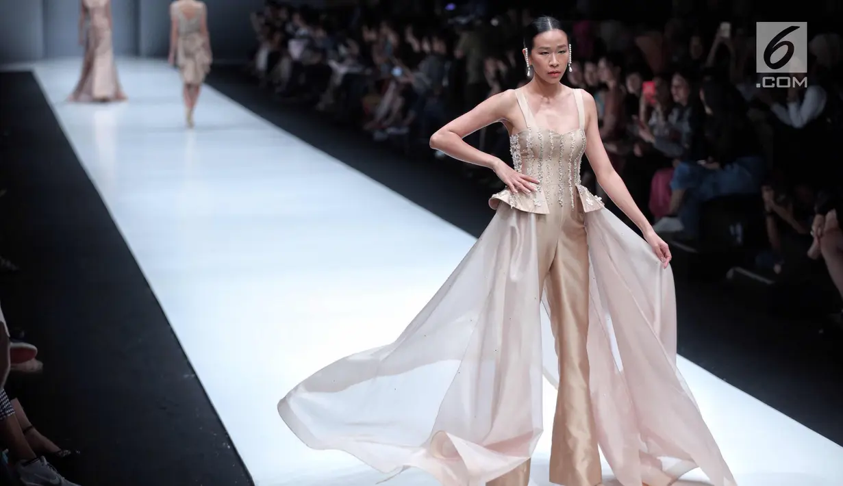 Model berpose diatas catwalk mengenakan rancangan desainer Cherryn Lim dalam ajang JFW 2018 di Senayan City, Jakarta, Kamis (26/10). Dalam rancangannya material yang digunakan bahan yang lembut, semi transparent dan glittery. (Liputan6.com/Faizal Fanani)