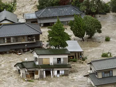 Warga yang terjebak luapan banjir dari Sungai Kinugawa di Joso, prefektur Ibaraki, menunggu dievakusi tim penyelamat, Jepang, Kamis (10/9). Satu orang hilang dan lebih dari 90 ribu warga diperintahkan untuk mengungsi. (REUTERS/Kyodo)