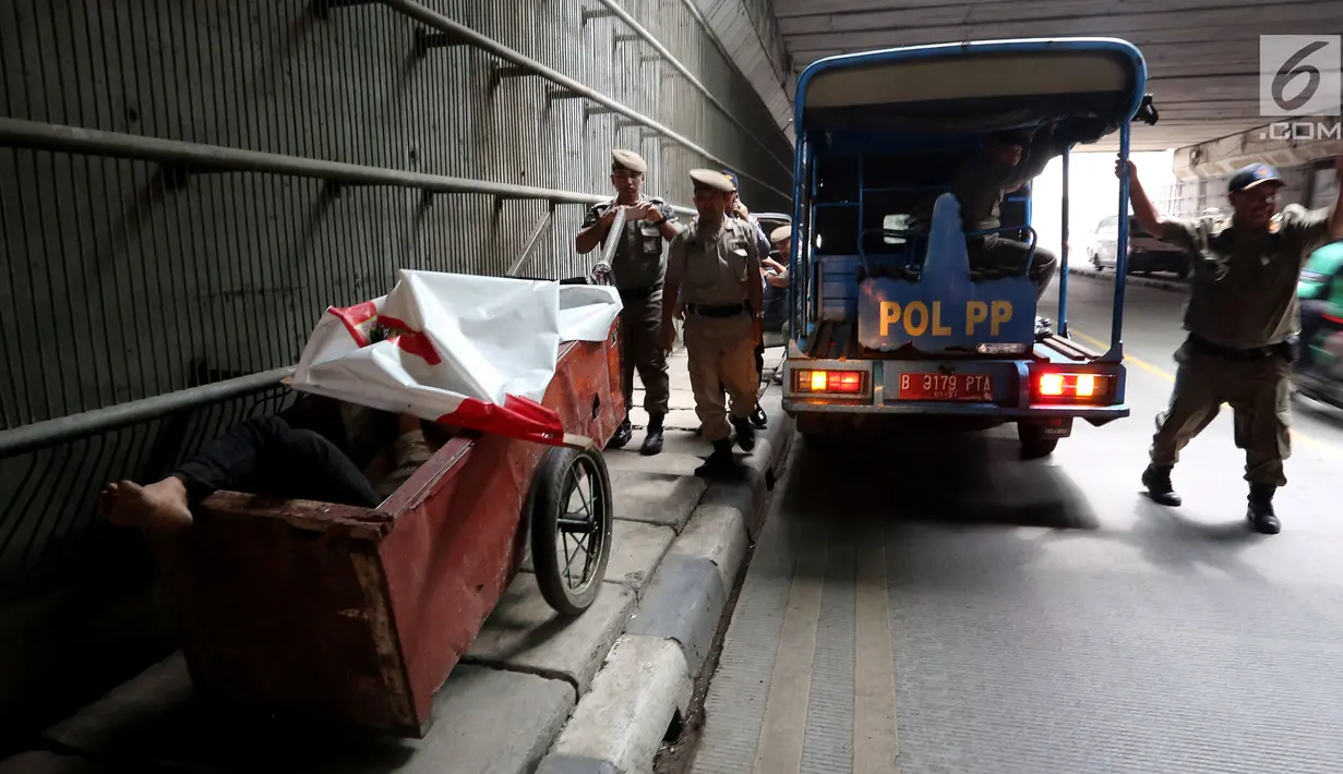 Petugas Satpol PP dari Kecamatan Setia Budi merazia tunawisma yang sedang sedang tidur di dalam gerobaknya di Kawasan Kuningan, Jakarta, Rabu (15/11). (Liputan6.com/JohanTallo)