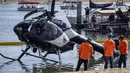 Sebuah derek digunakan untuk mengangkat helikopter Polisi Pantai Huntington di Pantai Newport, California (20/2/2022). Pihak berwenang sedang menyelidiki penyebab kecelakaan helikopter polisi di sepanjang pantai California Selatan tersebut. (Mindy Schauer/The Orange County Register via AP)