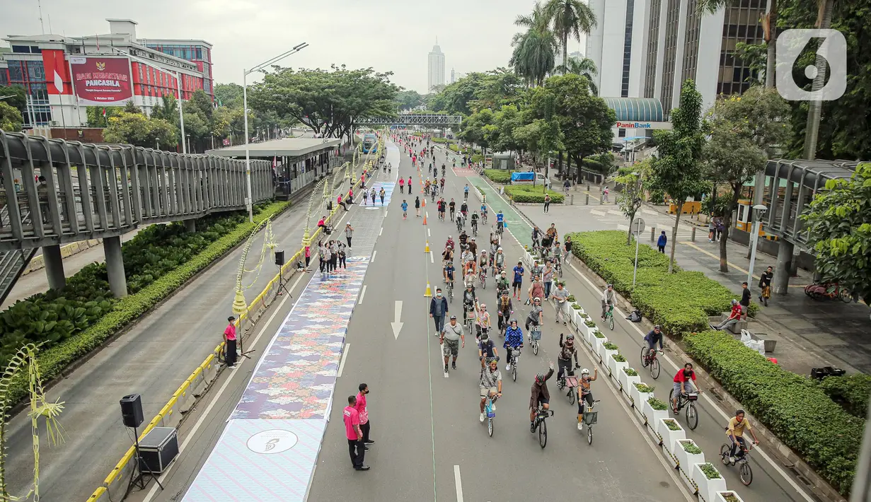 Suasana saat sejumlah orang yang mengenakan batik berjalan di catwalk sepanjang Jalan Jenderal Sudirman, Jakarta, Minggu (2/10/2022). Kegiatan yang diikuti ratusan orang ini diselenggarakan oleh Bank Mandiri untuk menyambut Hari Batik Nasional yang jatuh setiap tanggal 2 Oktober 2022. (Liputan6.com/Faizal Fanani)