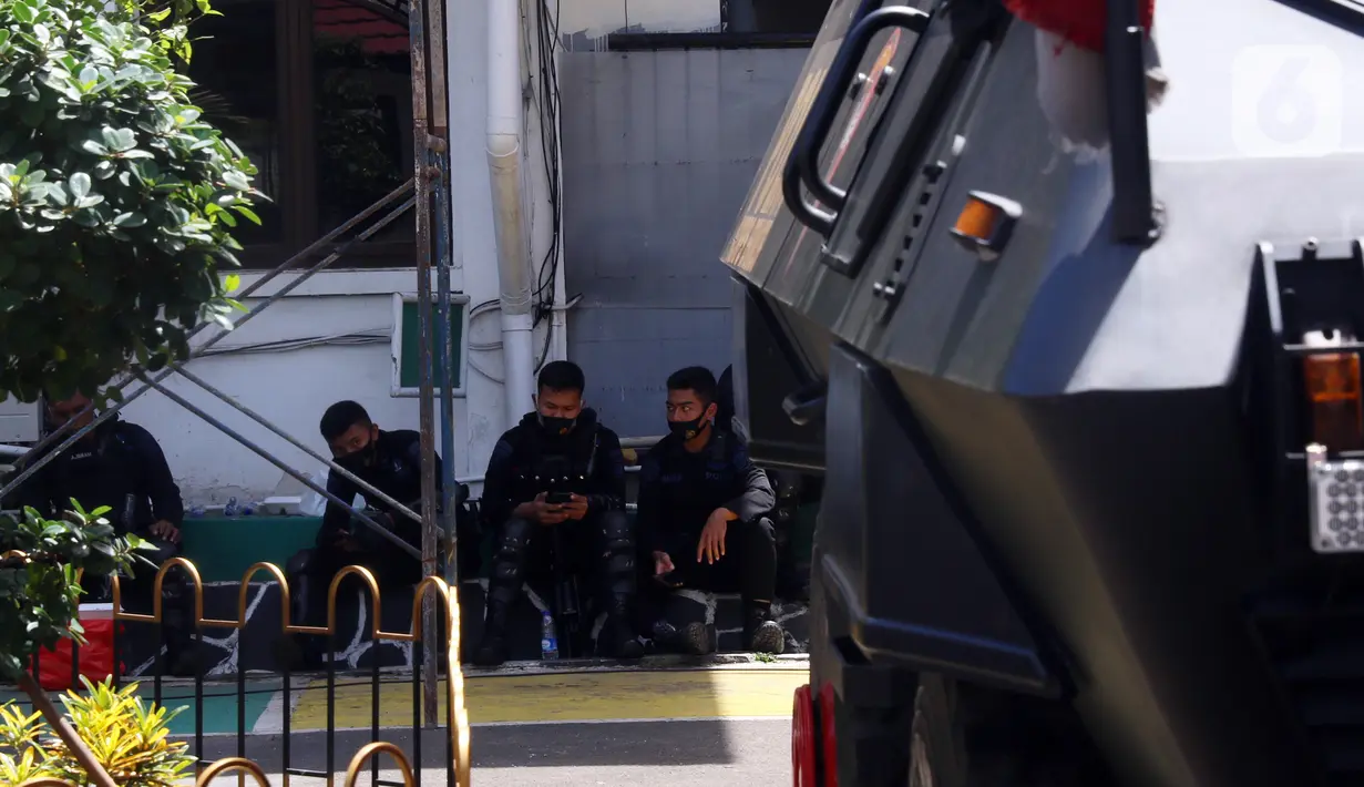 Sejumlah polisi beristirahat saat berjaga di area Pengadilan Negeri Jakarta Selatan, Senin (4/1/2021). Pengamanan ratusan aparat kepolisian dilakukan untuk mengantisipasi pergerakan masa pada saat sidang praperadilan Rizieq Shihab. (Liputan6.com/Angga Yuniar)