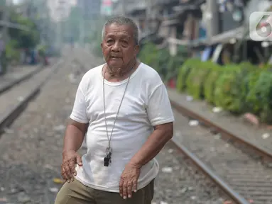 Penjaga perlintasan kereta api tanpa palang pintu, Wandi, menjaga perlintasan di Kawasan Petamburan, Jakarta, Jumat (4/6/2021). Sudah 10 tahun, Bapak Wandi menjaga palang pintu perlintasan kereta api yang kerap dilintasi oleh  pengguna jalan untuk menyeberang. (merdeka.com/Imam Buhori)