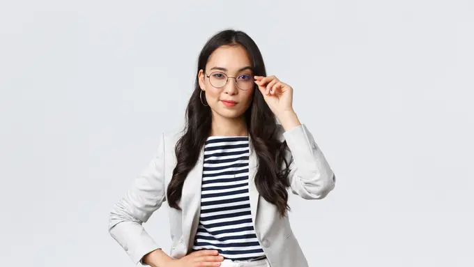 Seorang perempuan berkacak pinggang sambil memegang kacamata (Foto Dok: Freepik/benzoix)