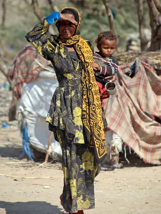 Seorang ibu bersama anaknya berjalan di kamp pengungsian Taez, Yaman (11/1). Jutaan warga melarikan diri hingga ke wilayah dataran tinggi seperti Taez. (AFP Photo/Ahmad Al-Basha)