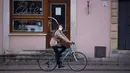 Seorang wanita mengendarai sepeda melewati sebuah kafe yang tutup di kawasan kota tua di Warsawa, Polandia (20/4/2020). Pemerintah Polandia juga mengizinkan sejumlah toko menerima lebih banyak pelanggan di gerai mereka. (Xinhua/Jaap Arriens)