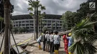 Petugas menumbangkan pohon yang rusak akibat ulah oknum suporter yang menyaksikan laga Final Piala Presiden 2018 di Stadion Utama GBK, Jakarta, Minggu (18/2) (Liputan6.com/Faizal Fanani)
