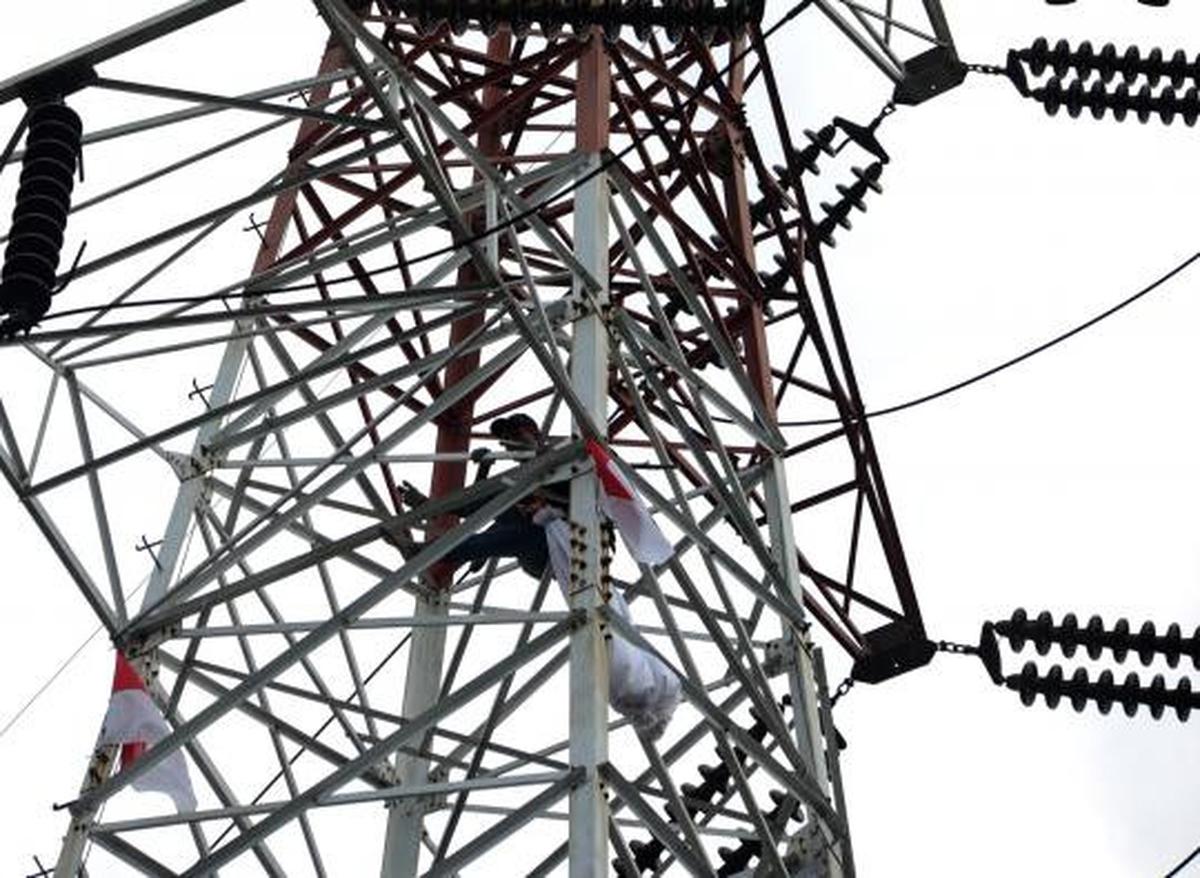 Pria berpakaian pocong di atas tower SUTET