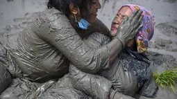 Petani bermain lumpur saat memeriahkan Hari Padi Nasional di desa Tokha di pinggiran Kathmandu, Nepal, Selasa (29/6/2021). Meski masih dalam suasana pandemi, peringatan Hari Padi tahun ini tetap digelar di bawah protokol kesehatan. (AFP/Prakash Mathema)