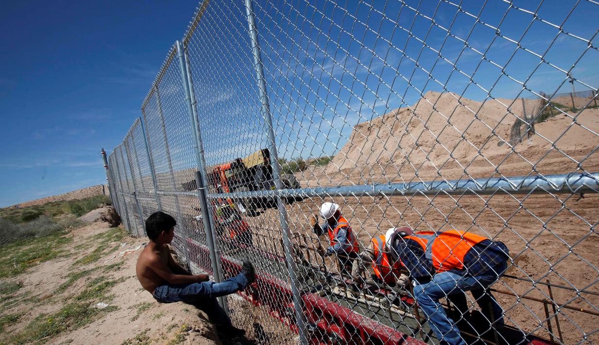 Seorang anak melihat pekerja dari Amerika Serikat saat membangun dinding perbatasan AS-Meksiko di Sunland Park, AS (09/9). Dinding perbatasan dibangun karena diduga sebagai pintu masuk imigran ilegal asal Mexico ke wilayah AS.(REUTERS/Jose Luis Gonzalez)