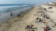 Pemandangan udara dari orang-orang di pantai di Playas de Tijuana dekat perbatasan AS-Meksiko di Tijuana, negara bagian Baja California, Meksiko, Sabtu (3/10/2020). Akhir pekan ini pantai di Playas de Tijuana dibuka kembali setelah ditutup sejak Maret lalu akibat Covid-19. (Guillermo Arias/AFP)