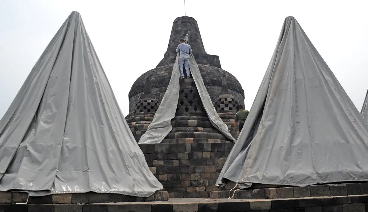 Seorang pekerja menutup stupa di kompleks candi Borobudur, Magelang, Jawa Tengah, Senin (23/11/2020). Penutupan candi Borobudur oleh BKB (Balai Konservasi Borobudur) sebagai langkah antisipasi melindungi batu candi dari abu vulkanik jika Gunung Merapi erupsi. (Photo by Agung Supriyanto/AFP)