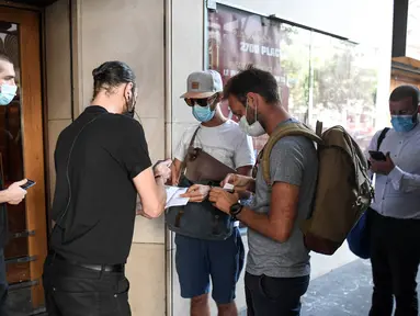 Penonton diperiksa paspor kesehatannya sebelum memasuki bioskop Grand Rex di Paris, Rabu (21/7/2021). Orang-orang yang pergi ke bioskop, museum atau pertandingan olahraga di Prancis harus membuktikan mereka telah divaksin atau hasil tes negatif Covid-19 yang berlaku selama 48 jam. (ALAIN JOCARD/AFP)