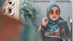 Penampilannya semakin lengkap dengan aksesoris kacamata berwarna oranye ini. Cocok dengan balutan hijabnya yang juga memiliki corak berwarna senada. (Liputan6.com/IG/@_irishbella_)