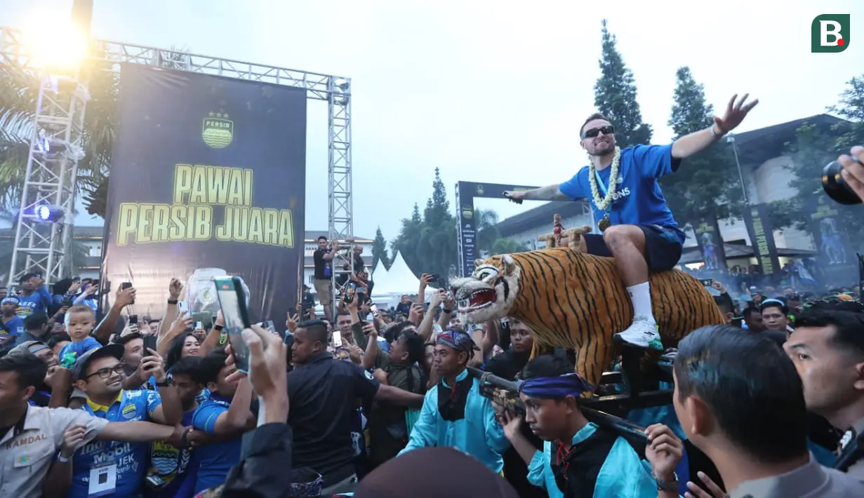 Gelandang Persib Bandung, Marc Klok diarak di atas Singa Depok menuju panggung utama setelah tiba bersama rombongan tim di Gedung Sate, Kota Bandung, Sabtu (1/6/2024) sore usai melakukan pawai juara BRI Liga 1 2023/2024. (Bola.com/M Iqbal Ichsan)