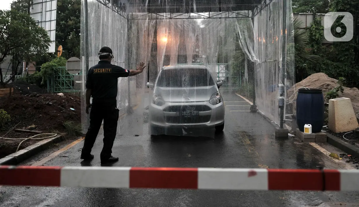 Petugas mengarahkan mobil saat memasuki bilik disinfektan di Perumahan Tamansari Persada Raya, Jatibening, Bekasi, Jawa Barat, Selasa (31/3/2020). Bilik disinfektan dipasang untuk mencegah penyebaran virus corona COVID-19 di area kompleks. (Iqbal S. Nugroho)