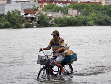 Curah hujan yang tinggi di Jakarta menyebabkan sejumlah kawasan terendam banjir. Tampak seorang mengayuh sepeda melintas di Danau Sunter yang meluap, Jakarta, Selasa (10/2/2015). (Liputan6.com/Faizal Fanani)