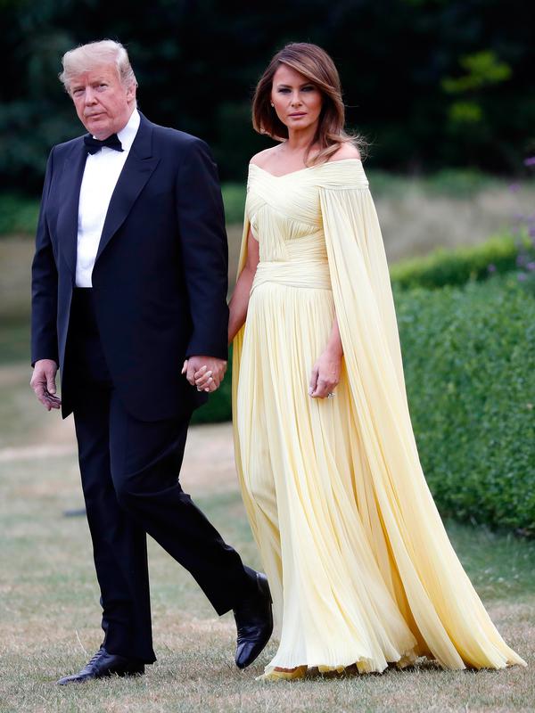 Presiden AS Donald Trump dan Melania Trump meninggalkan Winfield House di London, Kamis (12/7). Menghadiri acara makan malam, Melania terlihat begitu cantik dan anggun dalam balutan gaun panjang dengan 'cape' warna kuning. (AP/Pablo Martinez Monsivais)