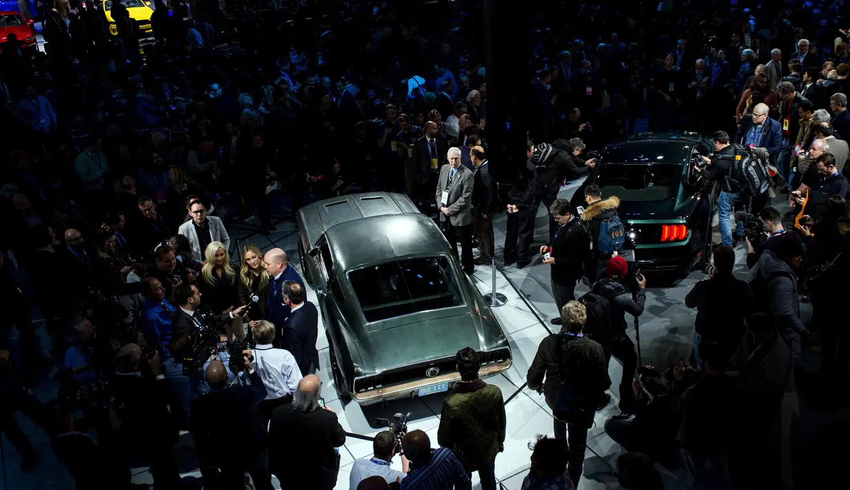 Pengunjung melihat mobil Ford Mustang Bullitt keluaran tahun 1968 yang dipamerkan bersebelahan dengan Mustang GT Fastback 2018 di North American International Auto Show, Detroit (14/1). (AP Foto / Carlos Osorio)