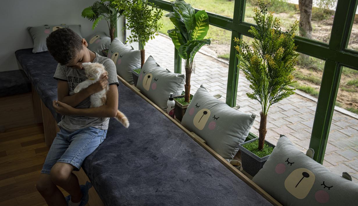 Aturan masuknya sederhana: Pengunjung harus menutup sepatu mereka dengan plastik dan mencuci tangan sebelum memeluk kucing. (AP Photo/Fatima Shbair)