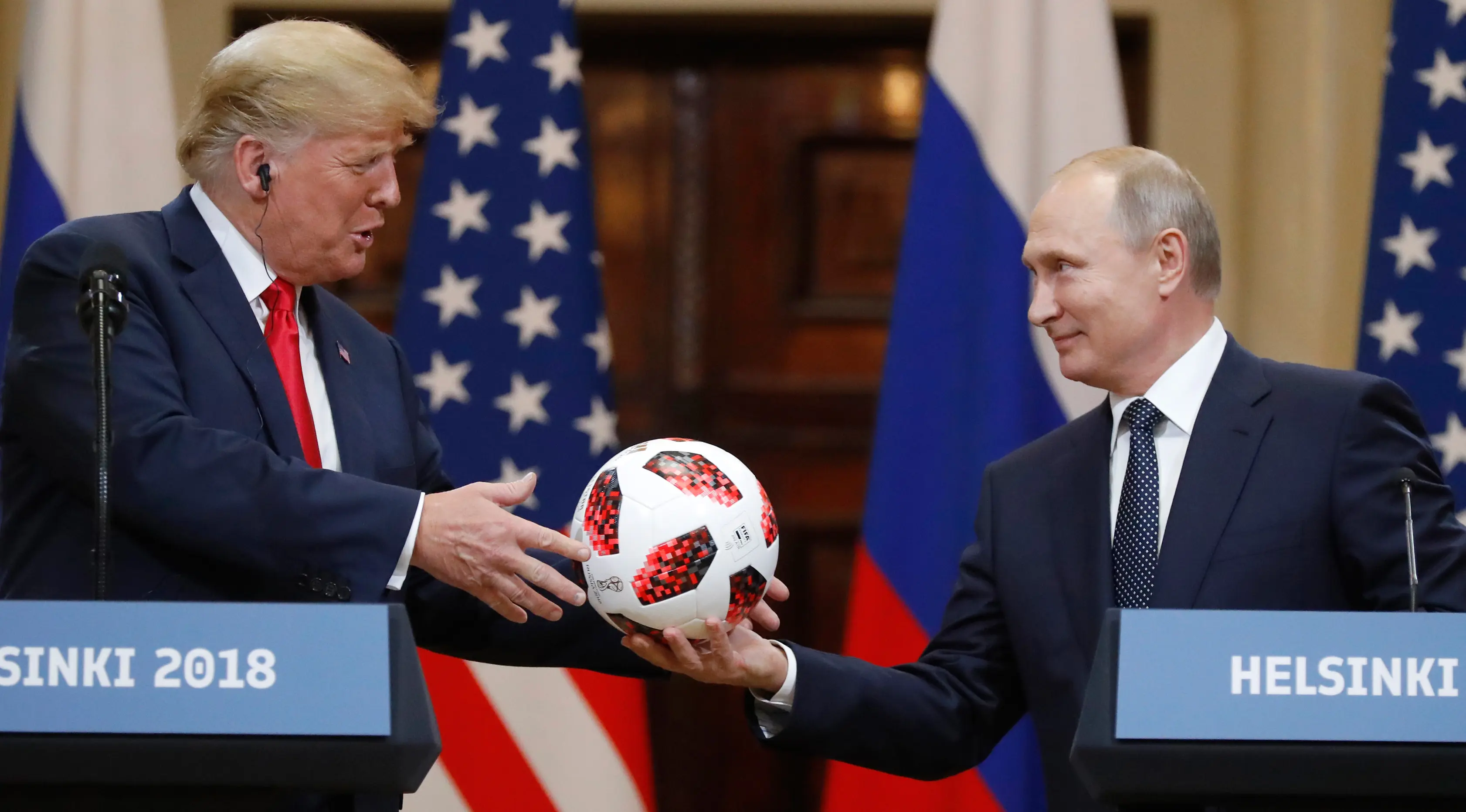 Presiden Rusia Vladimir Putin memberikan bola Piala Dunia 2018 kepada Presiden Amerika Serikat, Donald Trump selama konferensi pers bersama usai pertemuan mereka di Istana Presiden di Helsinki, Finlandia, Senin (16/7). (AP/Alexander Zemlianichenko)