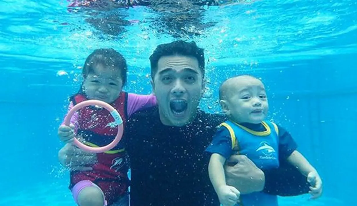 Tanpa memakai pelampung atau perlengkapan lainnya, Ricky Harun mengajak dua buah hatinya berfoto di dasar kolam renang. Terlihat ekspresi lucu dari papa ganteng yang satu ini dan dua anak mungil saat menahan napas ketika difoto. (Doc. Instagram)