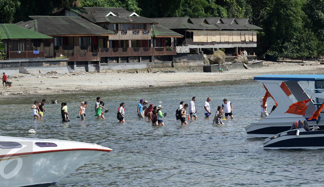 Sejumlah wisatawan mancanegara berjalan menuju kapal penumpang di Pulau Bunaken, Manado, Sabtu (17/12). Pemprov Sulut gencar melakukan promosi pariwisata dengan tujuan mendatangkan turis sebanyak mungkin hingga ke Tiongkok. (Liputan6.com/Fery Pradolo)