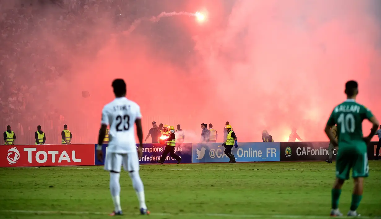 Petugas kepolisian memadamkan suar di Army Stadium, Alexandria, Mesir, (9/7). Suporter El Zamalek mengamuk setelah klubnya  gagal melaju di Liga Champions Afrika yang hanya mampu bermian 2-2 dengan Al Ahly Tripoli . (AFP Photo/Khaled Desouki)