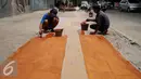 Pekerja sedang mengecat Trotoar Ramah Disabilitas di Jalan Hidup Baru, Kalimati, Jakarta Utara, Selasa (27/12). Pembangunan trotoar ini menggunakan material floor hardener di bagian tengah untuk jalur penyandang disabilitas. (Liputan6.com/Gempur M. Surya)