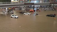 Sejumlah kendaraan melintasi banjir di sepanjang jalan setelah hujan lebat di Zhengzhou di provinsi Henan, China tengah (20/7/2021). Luapan sungai menggenangi jalan-jalan dan membuat kendaraan terbawa arus setelah curah hujan 200 mm turun dalam satu jam. (AFP/STR)