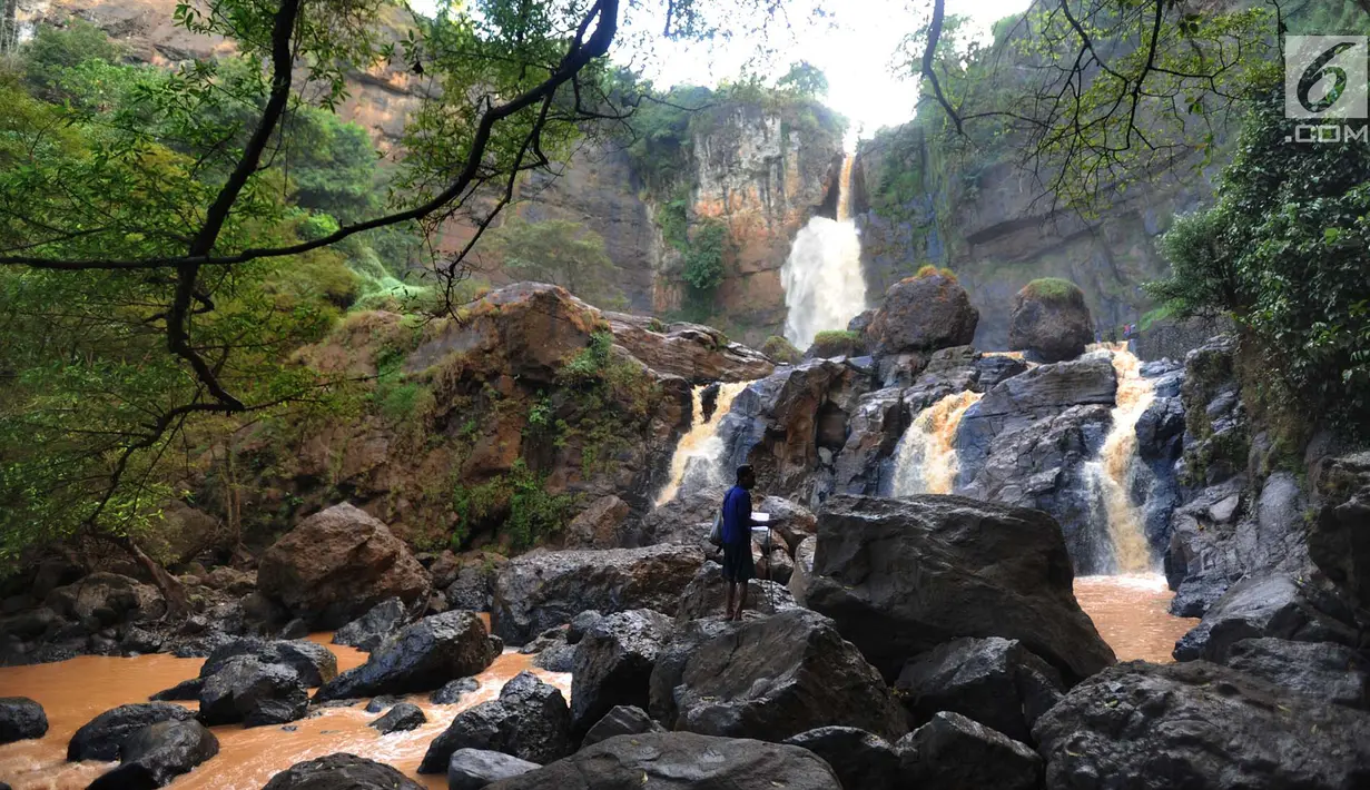 Pencari ikan berdiri di atas bebatuan Curug Cimarinjung, Kawasan Geopark Ciletuh, Sukabumi, Sabtu (23/6). Kawasan yang dikenal sebagai salah satu taman batu tertua di Pulau Jawa ini resmi mendapat predikat UNESCO Global Geopark. (Merdeka.com/Arie Basuki)