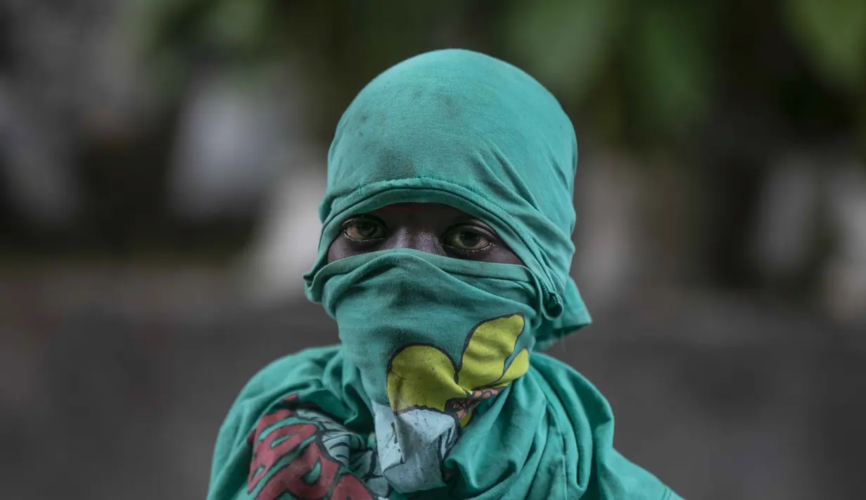 Seorang pengunjuk rasa menutupi wajahnya selama demonstrasi menuntut Perdana Menteri Haiti Ariel Henry mundur dan menyerukan kualitas hidup yang lebih baik, di Port-au-Prince, Haiti, Senin (29/8/2022). (AP Photo/Odelyn Joseph)