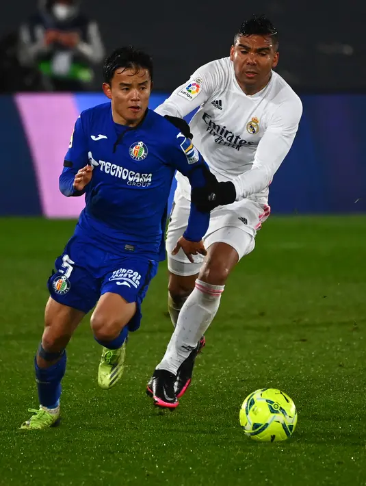 Gelandang Real Madrid, Casemiro (kanan) berusaha merebut bola dari gelandang Getafe, Takefusa Kubo (kiri) pada pertandingan lanjutan La Liga Spanyol di stadion Alfredo di Stefano di Madrid, Spanyol, Rabu (10/2/2021). Madrid kini memiliki 46 poin dari 22 pertandingan. (AFP/Gabriel Bouys)