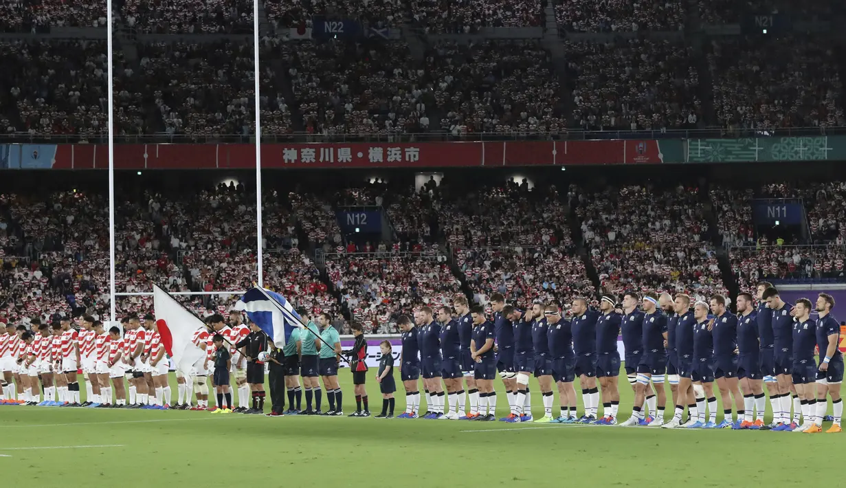 Pemain rugby Jepang dan Skotlandia berdoa bersama selama satu menit untuk korban Topan Hagibis sebelum Pertandingan Pool A Piala Dunia Rugbi 2019 di Stadion Internasional Yokohama (13/10/2019). (AP Photo/Eugene Hoshiko)