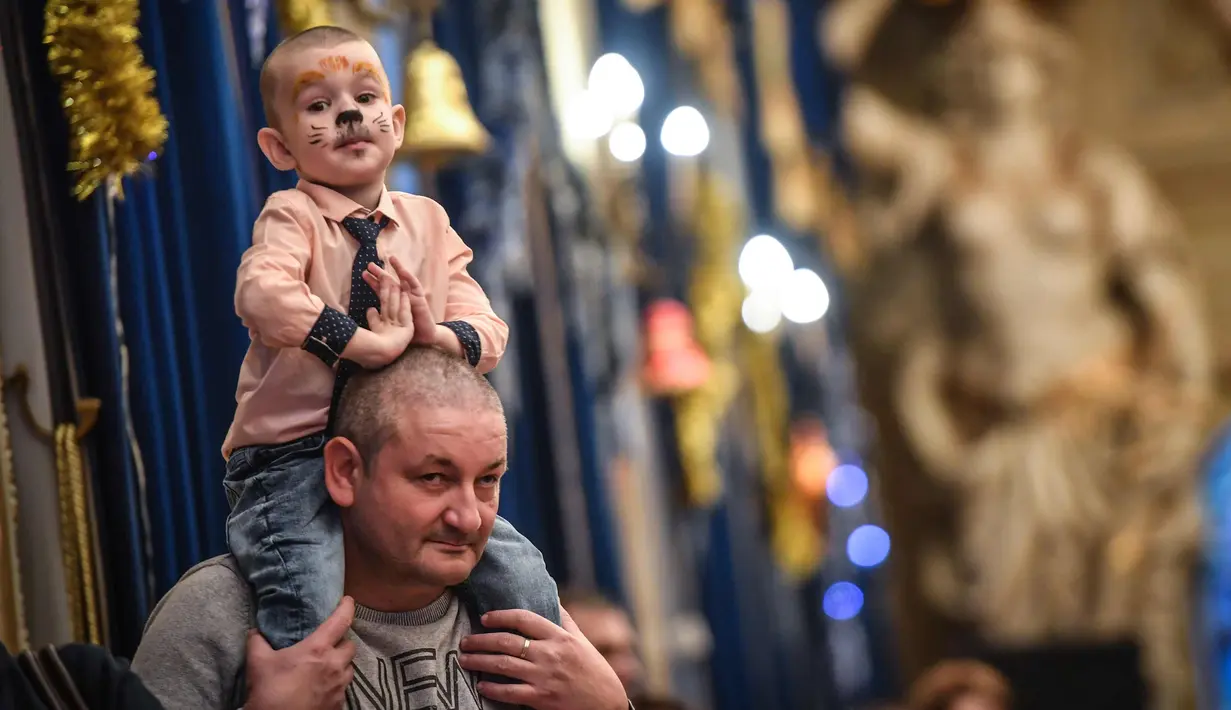 Seorang anak duduk di pundak ayahnya mengikuti acara Natal di Istana Militer Nasional di Bucharest, Rumania, (21/12). (AFP Photo/Daniel Mihailescu)