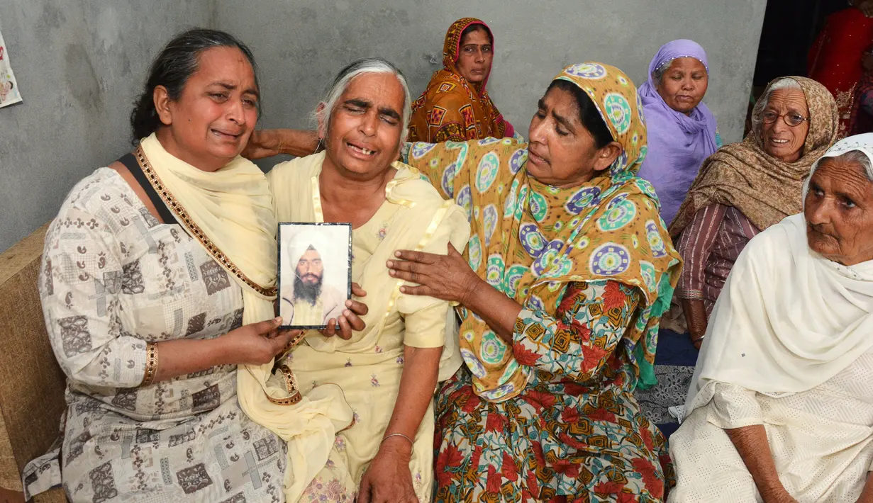 Keluarga berduka sambil menunjukkan potret Gurcharan Singh yang jasadnya ditemukan terkubur di barat laut Mosul, India (20/3). Sebanyak 39 warga India yang diculik oleh Kelompok ISIS pada 2014 dikonfirmasi telah tewas. (AP/Prabhjot Gill)